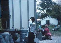 Actor Kyle Johnson (Newt Winger) taking a drink, while other actors sit in the background.