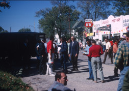 Actors and crew preparing for a scene in downtown Fort Scott, Kansas. Director Gordon Parks (in blue denim) gives instructions, center. Stephen Perry (Jappy), in blue shirt and jeans, consults a book.